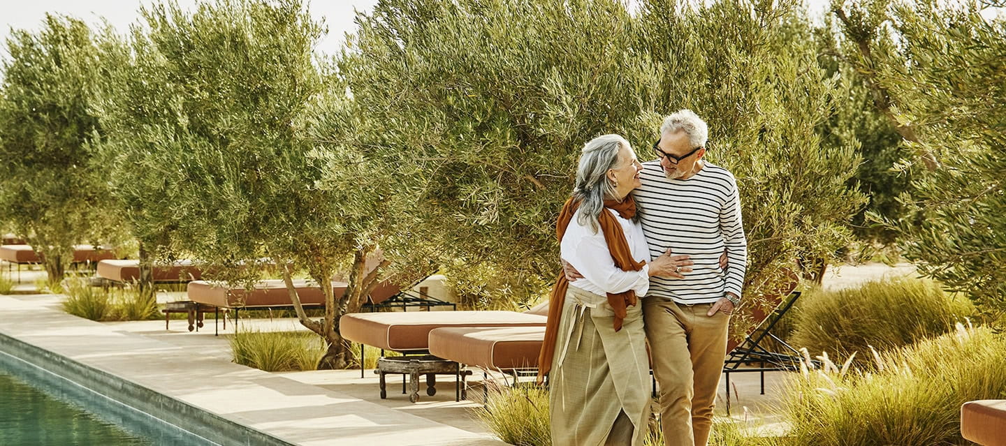 A mature couple walking next to a hotel swimming pool in Autumn