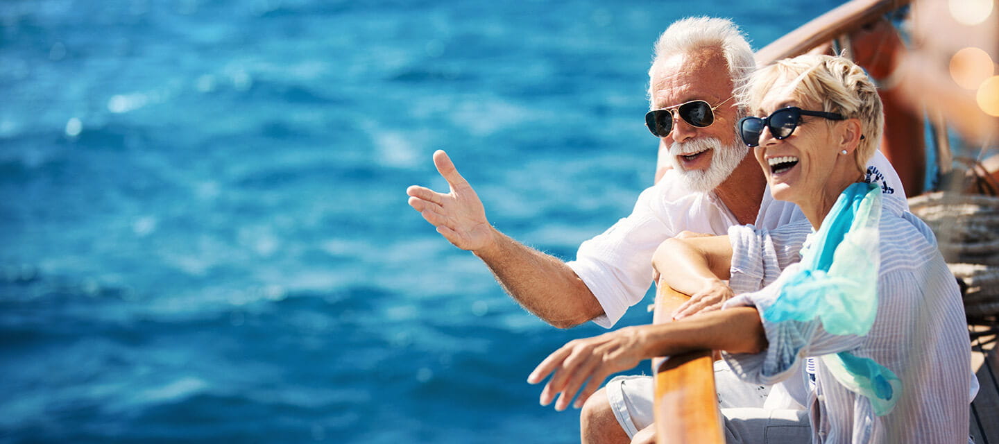 Closeup side view of mid 60's couple enjoying a sailing cruise during summer vacation at seaside.