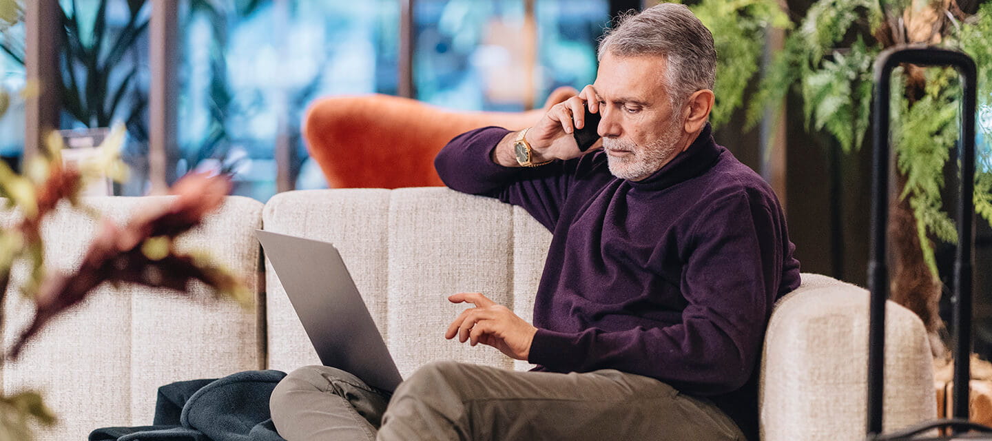 Mature man talking on mobile phone while sitting at hotel lobby