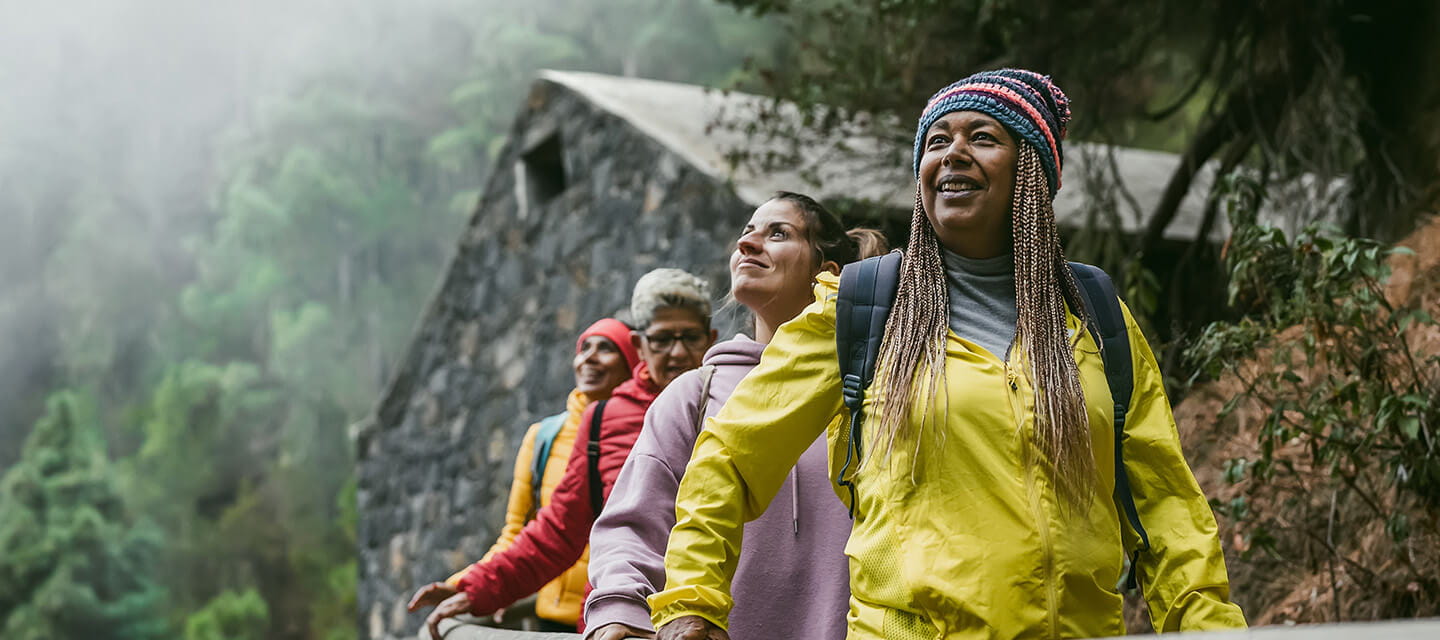 Group of women with different ages and ethnicities having fun walking in foggy forest