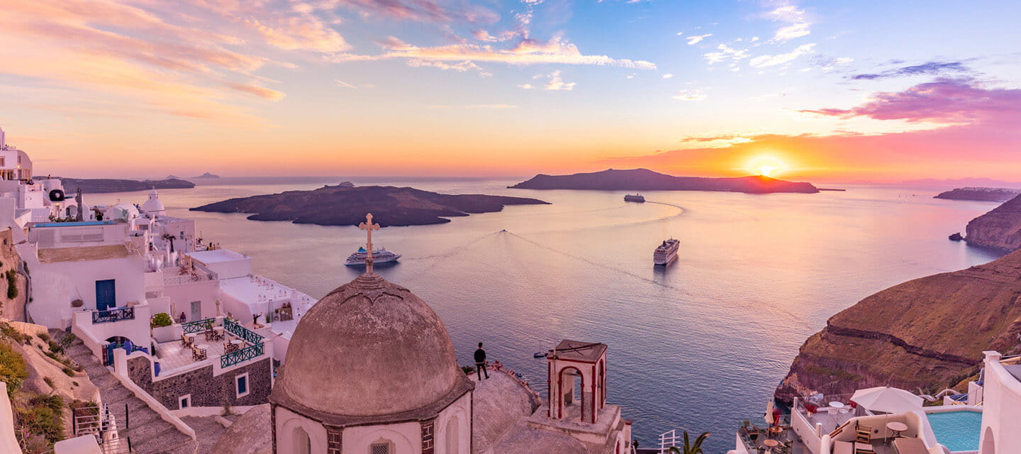 Aerial shot of a cruise ship passing by a shore line at sunset