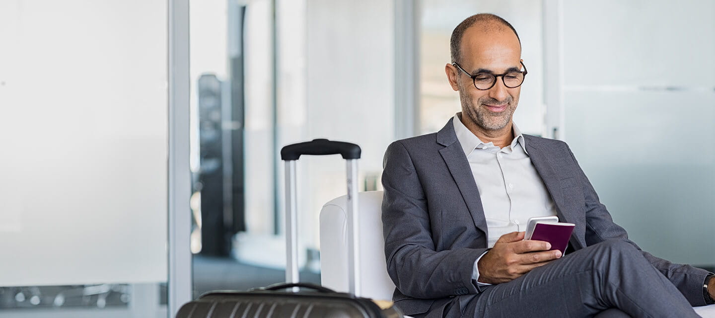 Mature man using mobile phone at the airport in the lounge area.