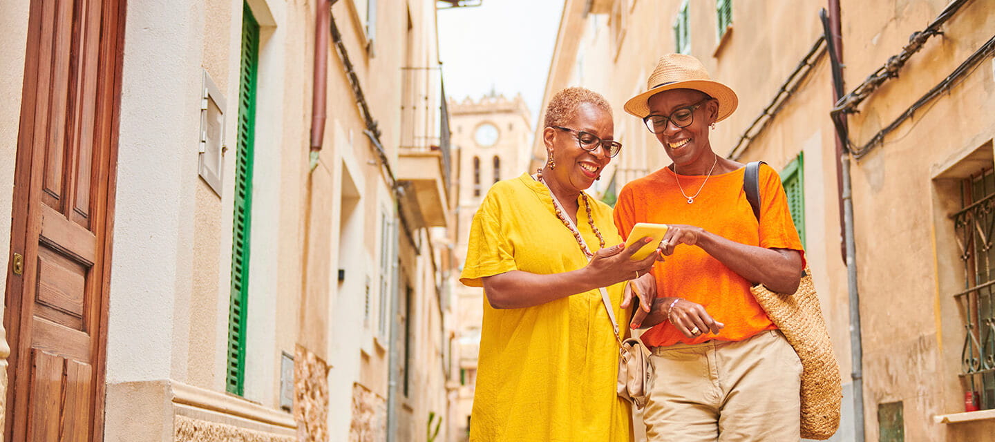 Two mature women walking together exploring an old town in Europe.