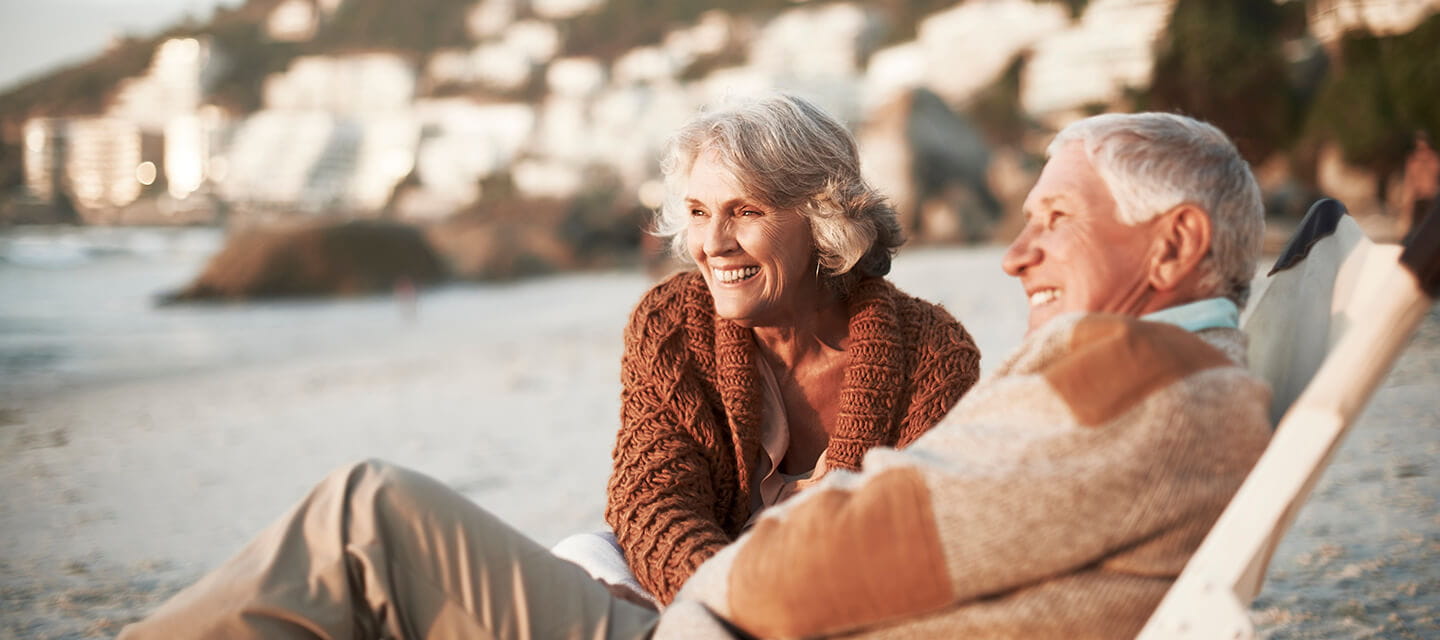 Happy senior couple relaxing on deck chairs at the beach