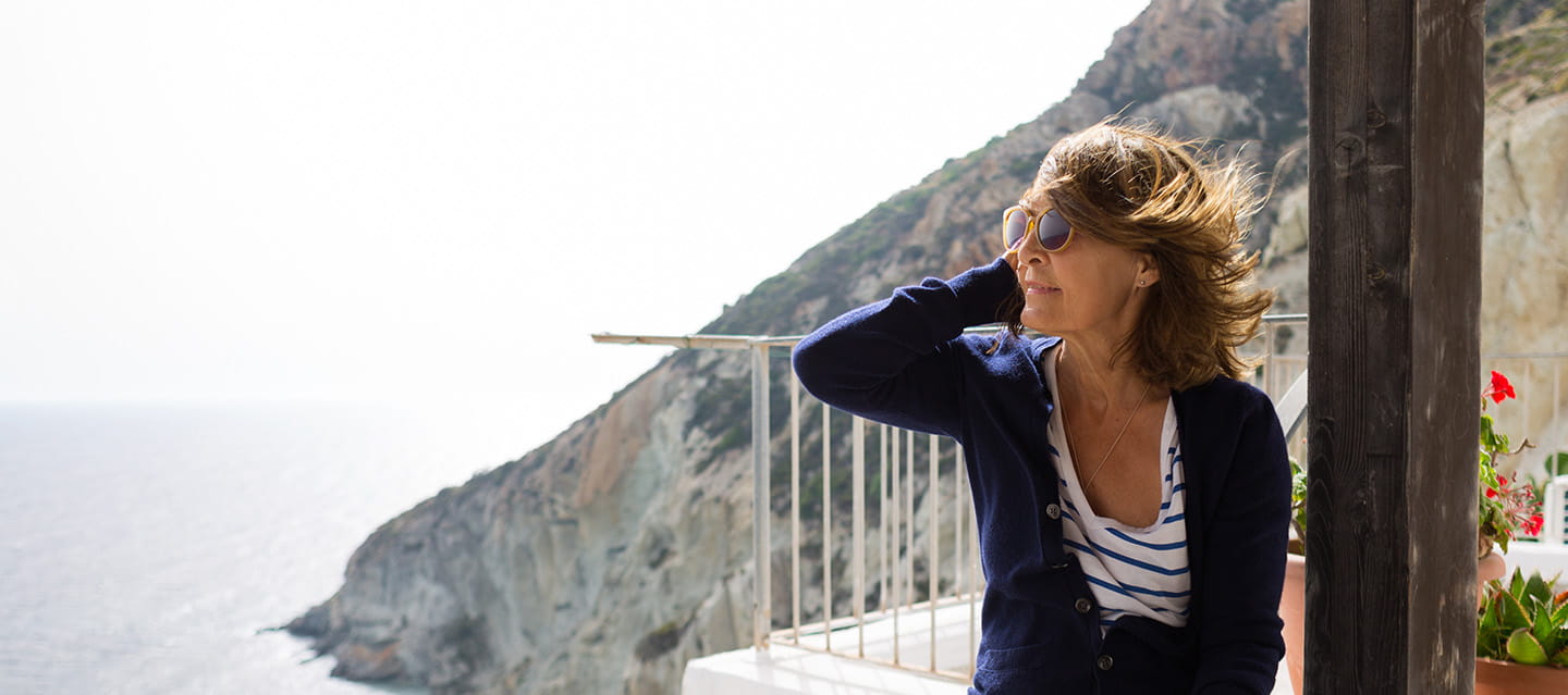 Senior woman enjoying breakfast on a seaside terrace