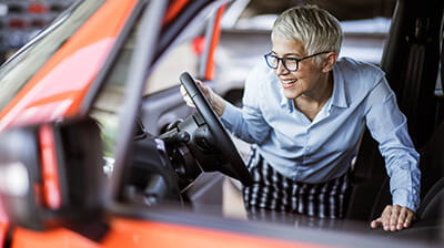 Happy mature woman buying a car in a showroom.