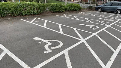 A row of disabled parking bays in a public car park, painted with white paint