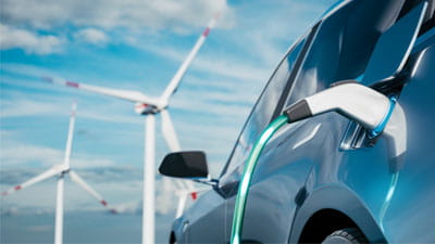 An electric car on charge near a wind farm