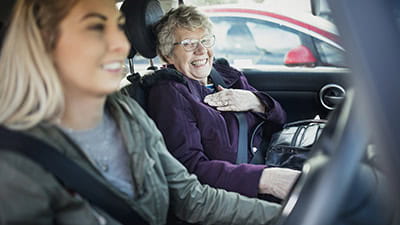 Young woman driving with her Grandmother sitting in the passenger seat.