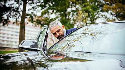 A mature man getting into his luxury car