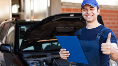 A mechanic giving a thumbs up whilst holding a clip board 