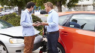 Two drivers exchange insurance details after accident.