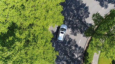 Aerial view of a car driving in a leafy suburb
