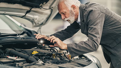 A mature man looking under the bonnet of a used car
