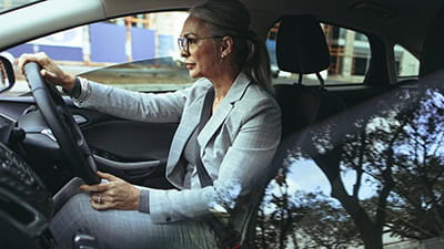 Mature woman in business suit driving a car to office.