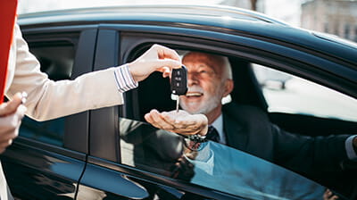 A man being handed the keys to a car he has purchased