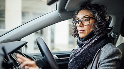 A mature woman dressed for cold weather driving in her car