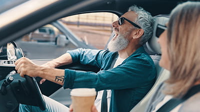 A senior couple laughing at a joke while driving 