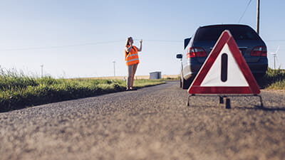 Long blondhaired woman have car breakdown in a rural landscape.