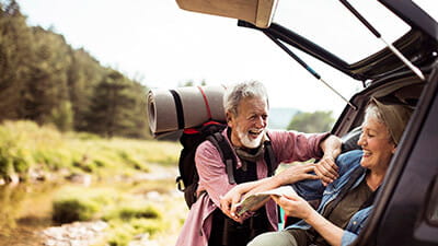 A happy couple getting ready to go hiking at the boot of their car