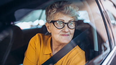 An elegant mature lady gazing longingly out of her car window