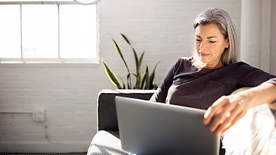 A woman sitting in a nice apartment browsing on her laptop