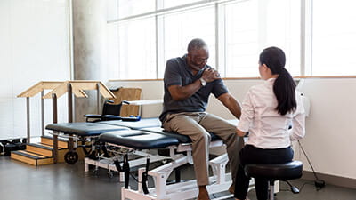 Senior man with an injured shoulder in rehab clinic