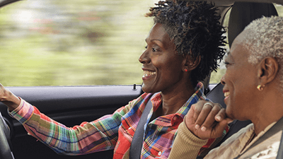 Two smiling women driving with the window down