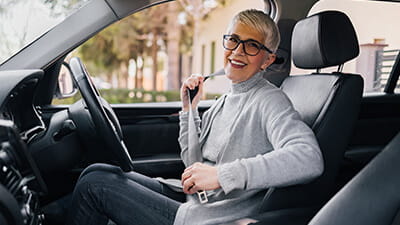 A stylish woman smiling while putting her car seatbelt on