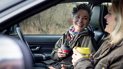 Two women sitting in a car talking and laughing together after a walk.