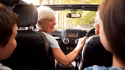 A happy couple enjoying a drive with their grandchildren