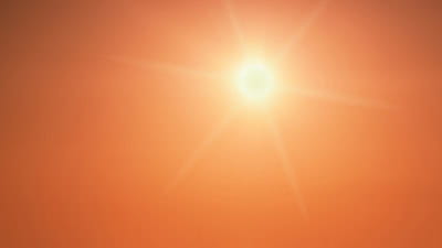 The sun shining brightly in a clear orange sky