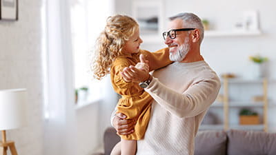 A smiling man holding his granddaughter