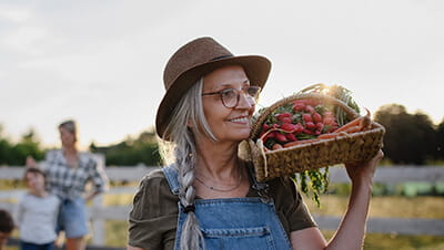Mature woman carrying basket with homegrown vegetables outdoors