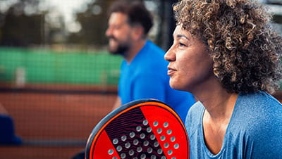 Side view portrait of adult couple playing padel on outdoor court.