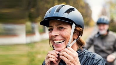 An active mature woman smiling while wearing a bike helmet