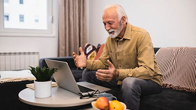 A mature man talking on a video call via his laptop