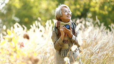 Mature woman taking pictures with camera in autumn park.