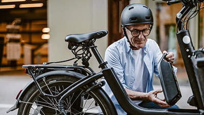 Senior man changing battery on electric bicycle