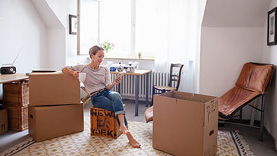 A mature woman taking a break from packing boxes in her living room