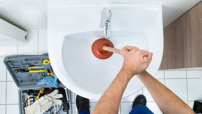 Close up aerial view of a plumber using a plunger on a sink