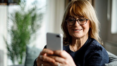 A mature lady sat at home looking at her mobile phone