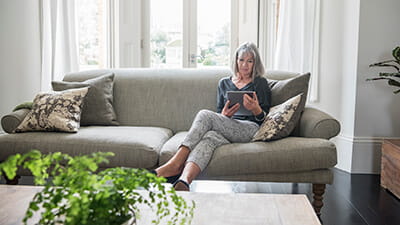 Senior woman sitting relaxing on the sofa using digital tablet