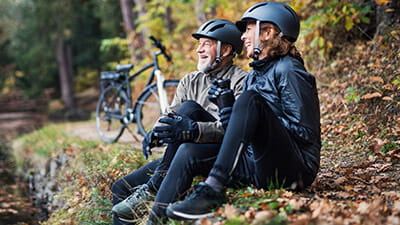 A couple of cyclists relaxing next to a river in autumn