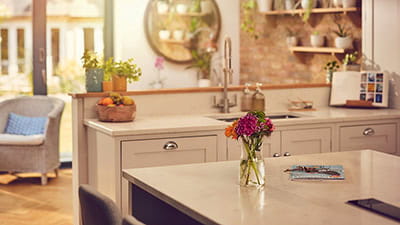 A close up shot of a vase containing flowers stood on a kitchen island