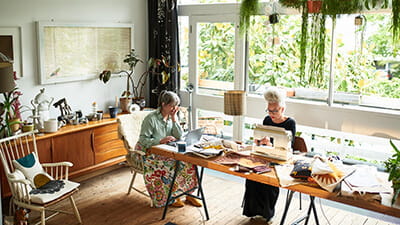Two craft enthusiasts working at dining room table