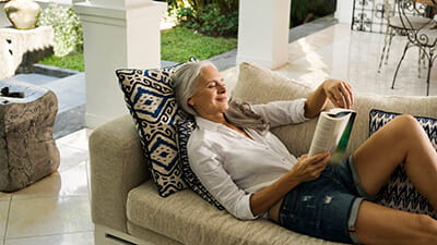 Elegant senior woman relaxing on couch, reading a book