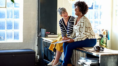 Two women sat on a counter laughing while listening to records