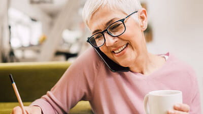 A mature woman talking on her mobile phone while making notes