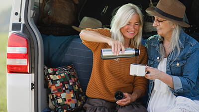 Two women sat drinking coffee on the back of their motorhome